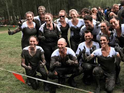 A group of people are posing for a picture while covered in mud.