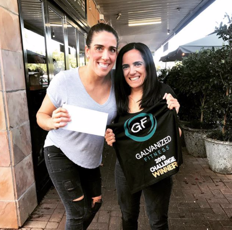 Two women are standing next to each other holding a sign that says galvanized fitness