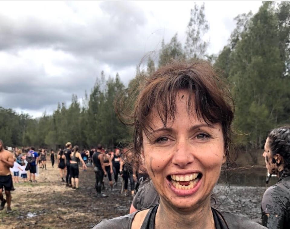 A woman is smiling while standing in the mud.