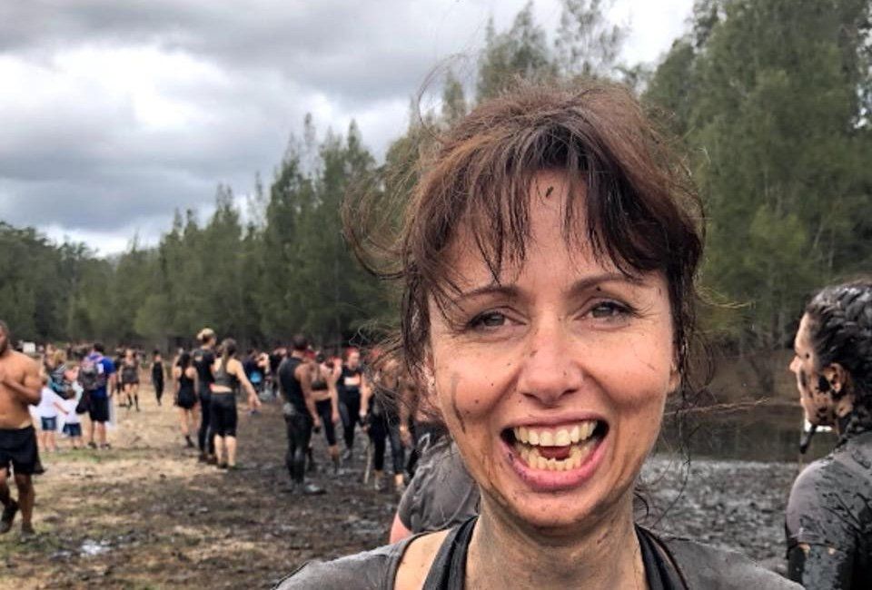 A woman is smiling while standing in the mud.