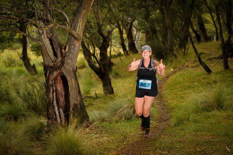 A woman is running through a forest on a trail.