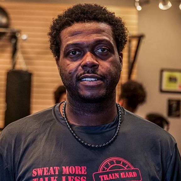 A man wearing a shirt that says sweat more talk less
