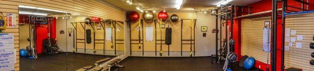 A gym with a lot of equipment and a lot of mirrors.