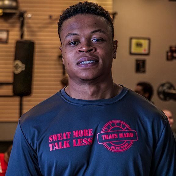 A man wearing a shirt that says sweat more talk less