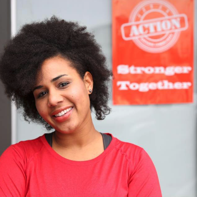 A woman stands in front of a sign that says action stronger together