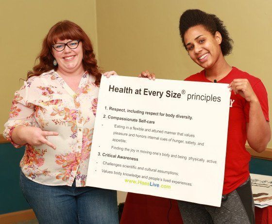 Two women holding a sign that says health at every size principles