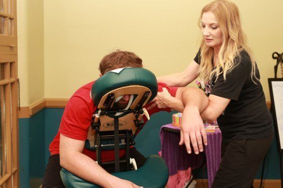 A woman is giving a man a massage in a chair