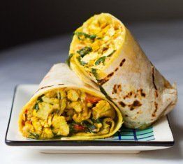 Two burritos are on a plate on a table.