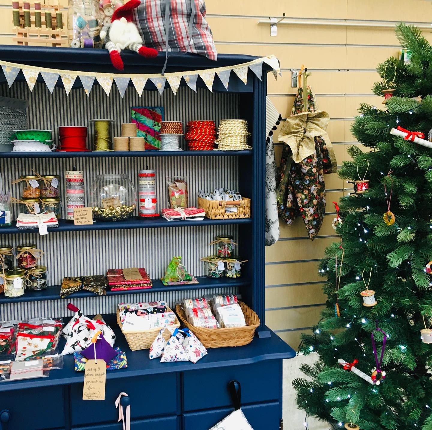 A christmas tree is in front of a shelf full of christmas decorations