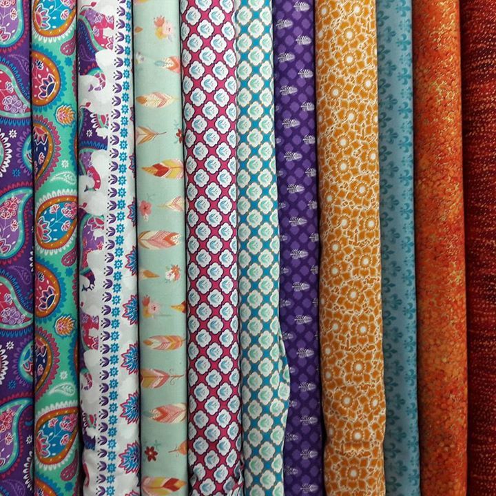 A bunch of different colored fabrics are lined up in a row.