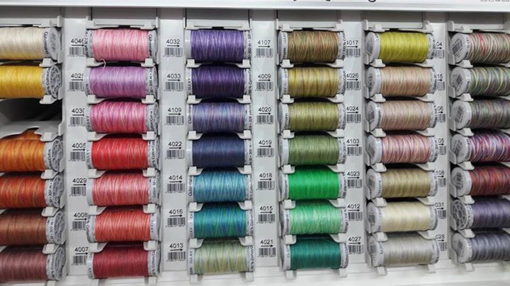 A bunch of spools of thread are lined up on a shelf