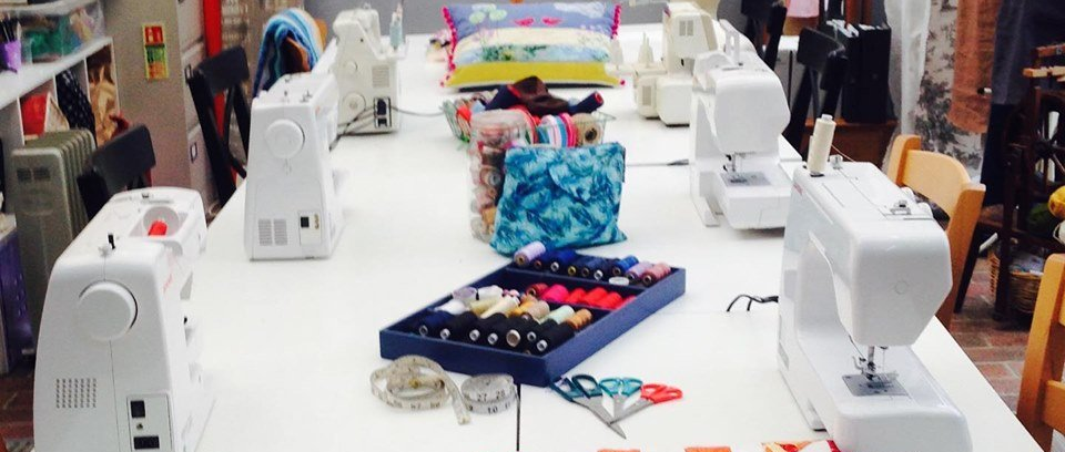 A row of sewing machines are lined up on a table.