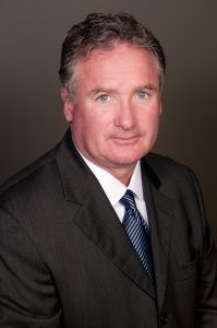 A man in a suit and tie is smiling for the camera.