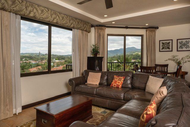 A living room with a couch , coffee table , and large windows.