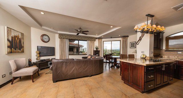 A living room with a couch , chair , television , and kitchen.