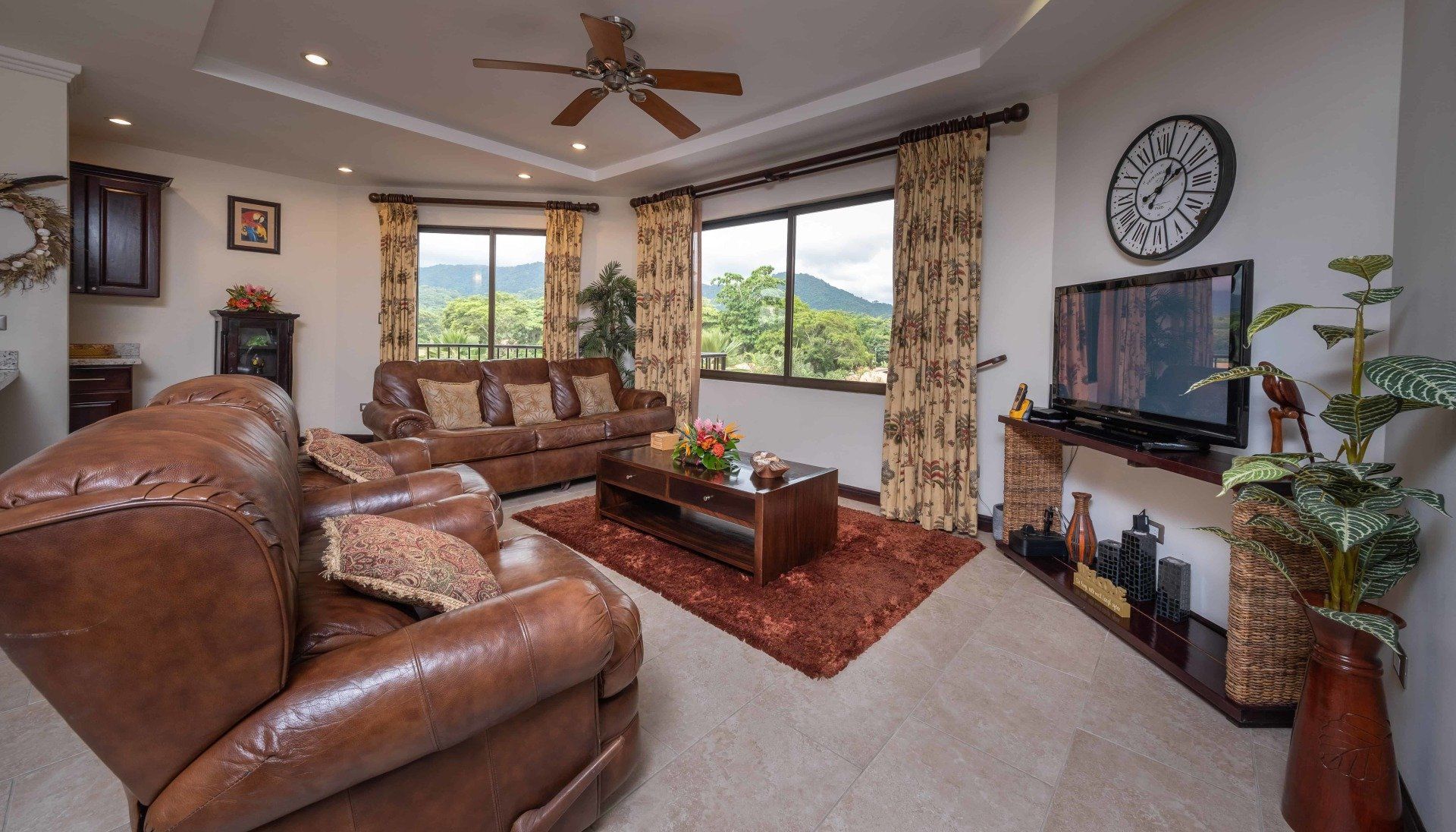 A living room with brown furniture and a clock on the wall