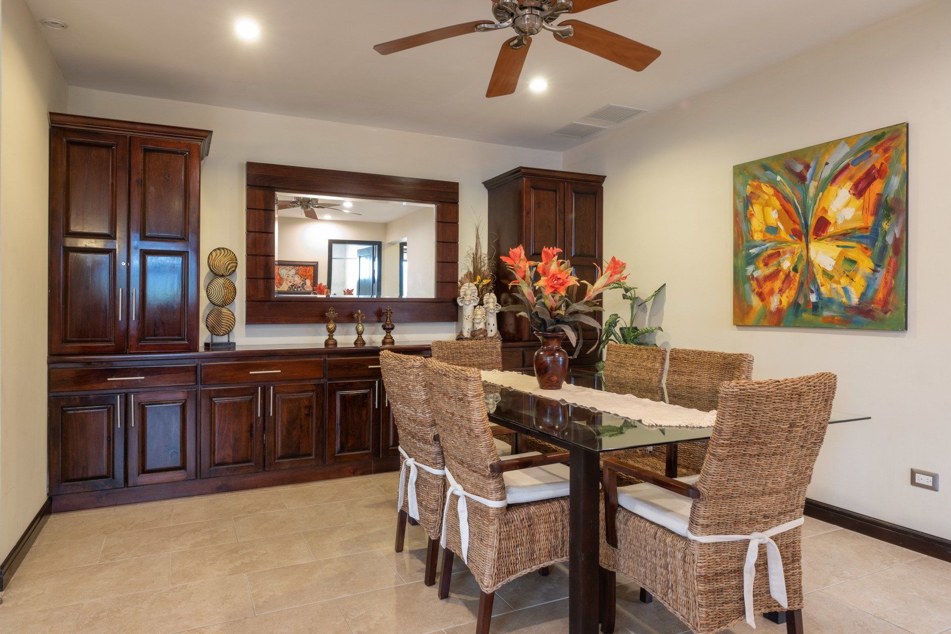 A dining room with wicker chairs and a butterfly painting on the wall