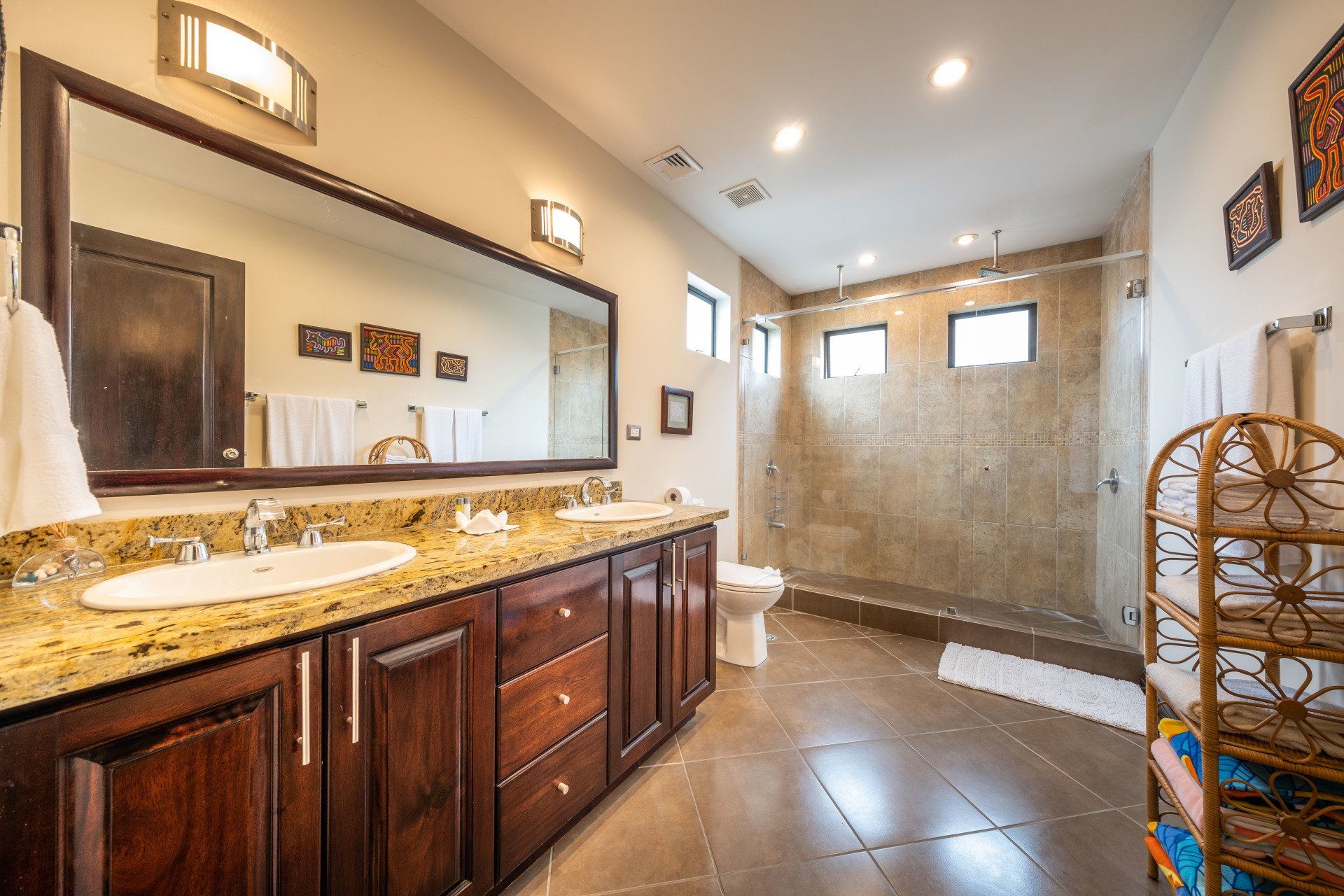 A bathroom with two sinks , a toilet and a walk in shower.