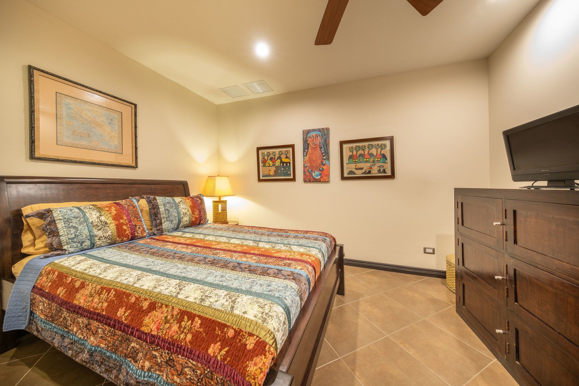 A bedroom with a king size bed , dresser , and television.