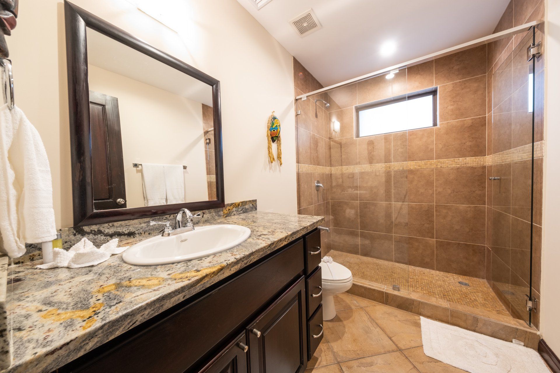 A bathroom with a sink , mirror , toilet and walk in shower.