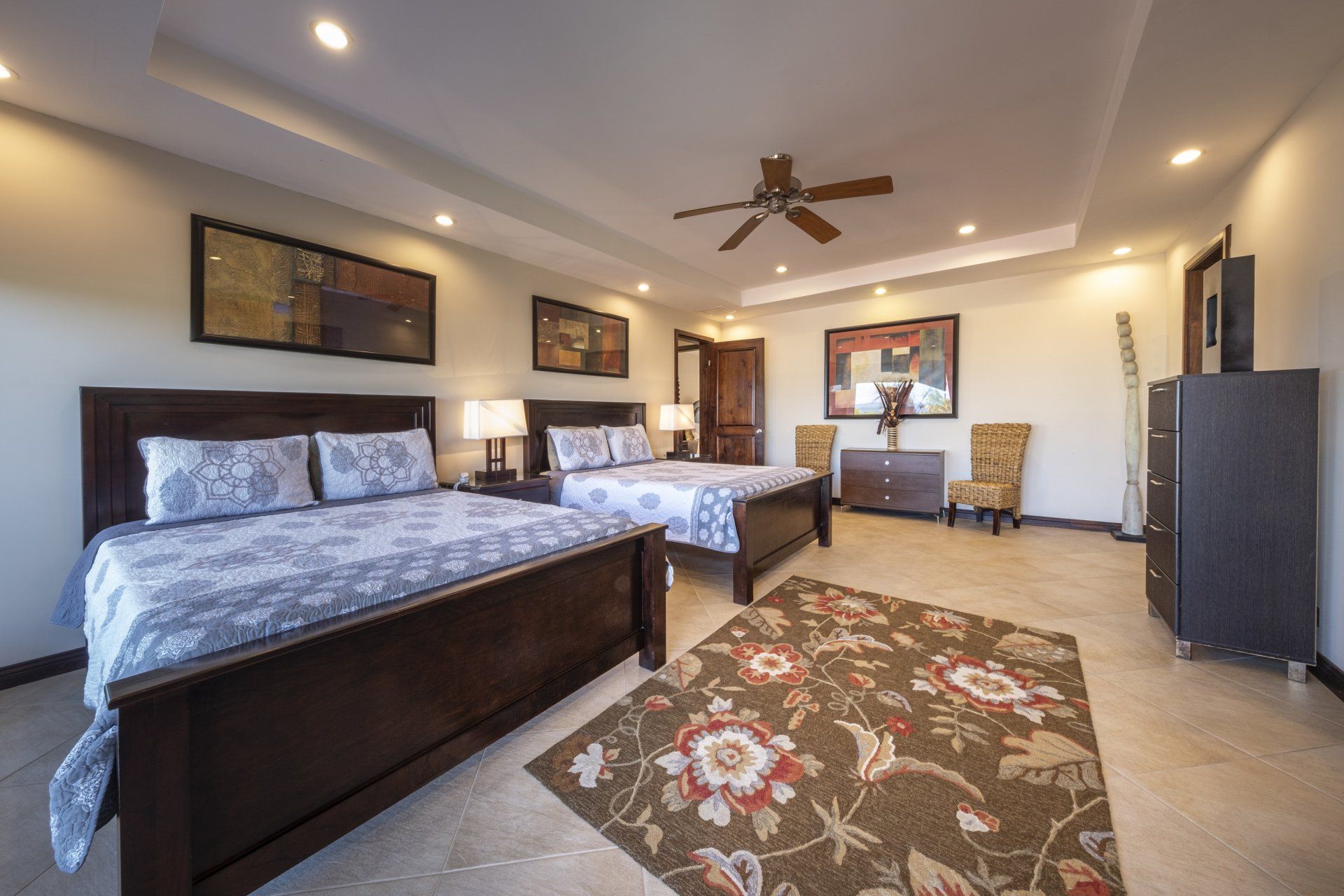 A bedroom with two beds , a rug and a ceiling fan.