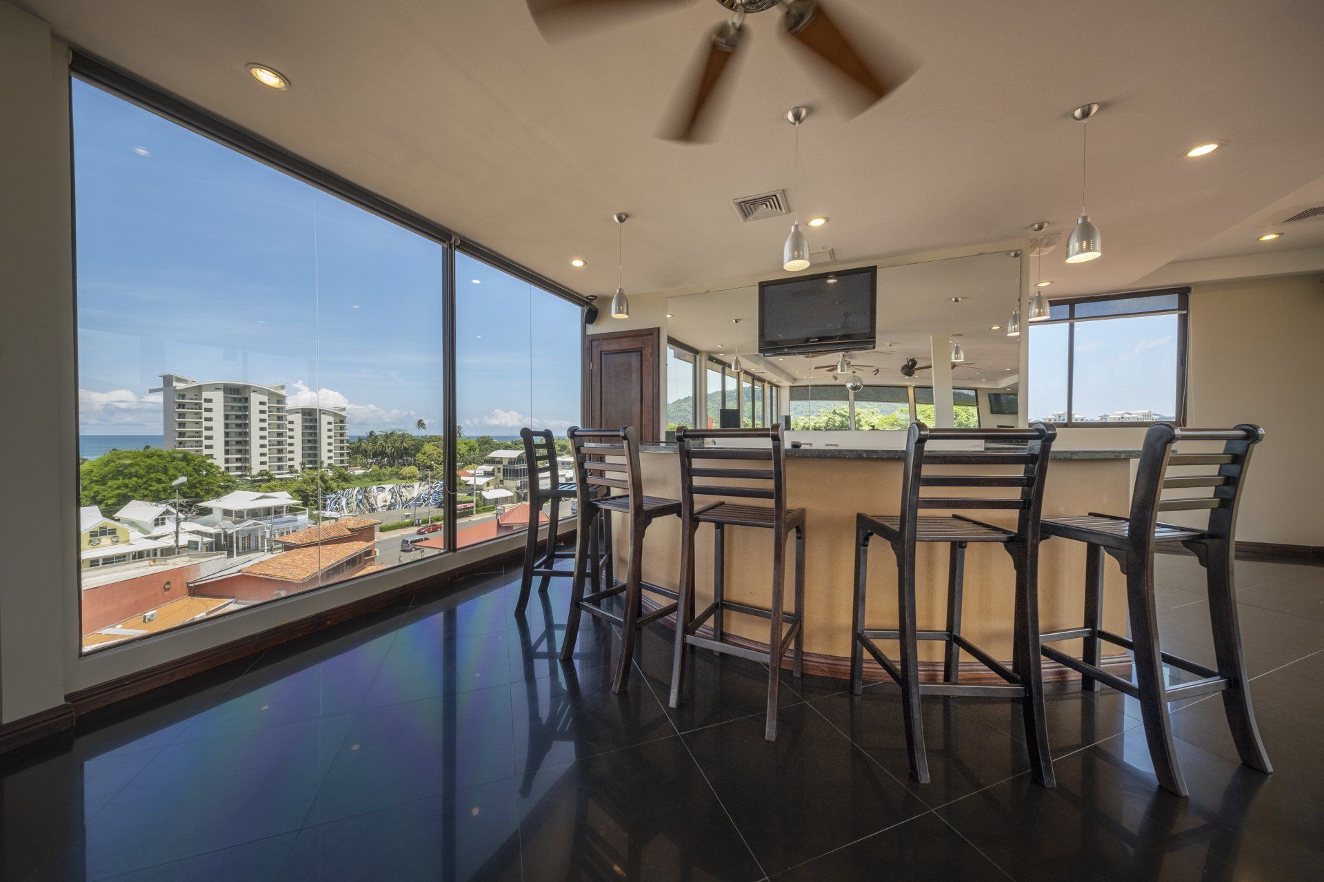 A large room with a bar and stools and a view of the ocean