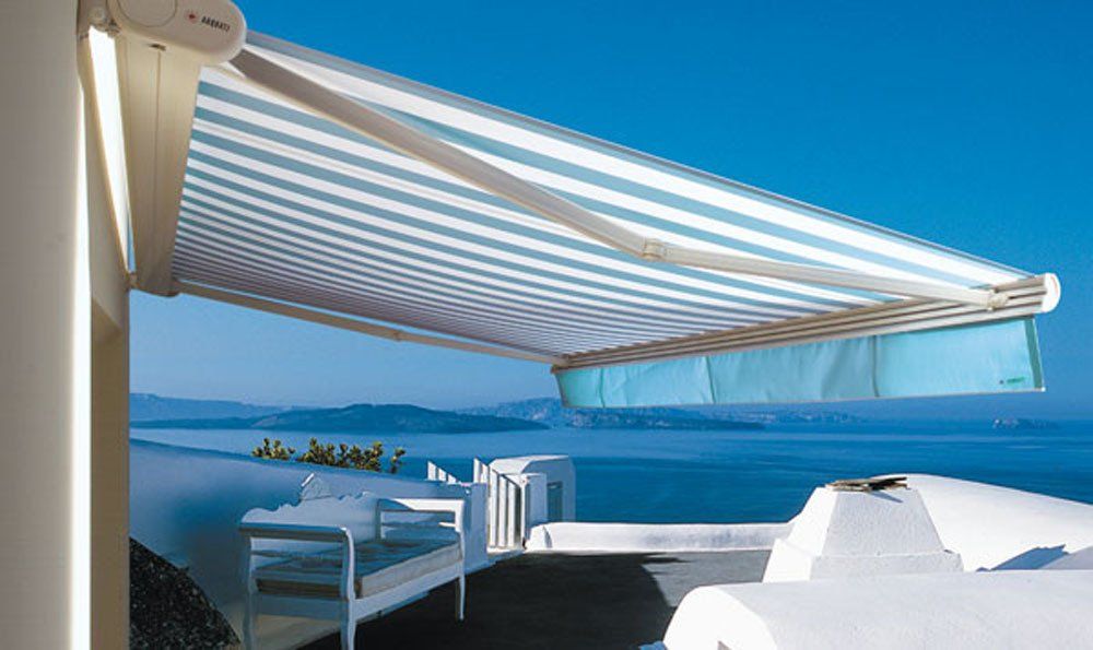 Tenda a strisce blu e bianche su una terrazza sul mare, con l'oceano sullo sfondo.