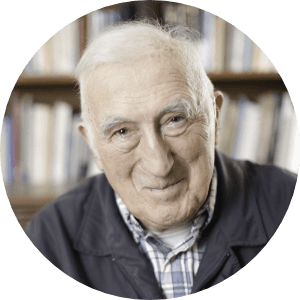 Smiling man in a dark jacket in front of a bookshelf