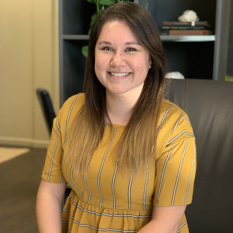 Smiling woman in a mustard striped top seated in an office chair