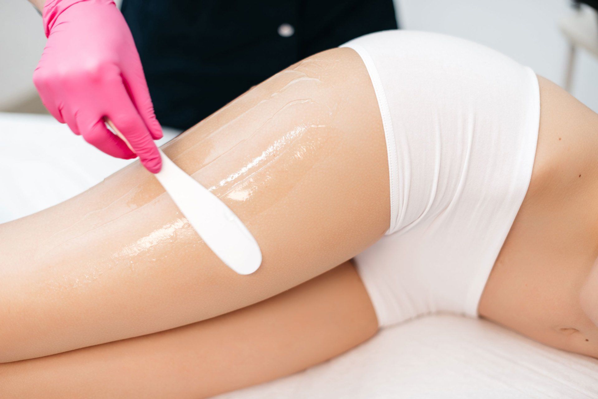 A woman is getting a wax on her leg in a beauty salon.