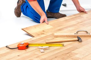 Resurface Hardwood — Man Laying Laminate Flooring in Casper, WY Resurface Hardwood — Man Laying Laminate Flooring in Casper, WY