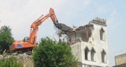 scavatrice che demolisce una casa