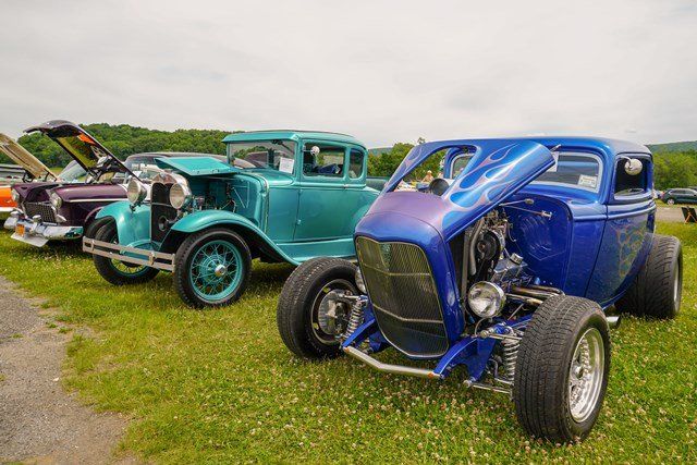 A row of old cars are parked in a grassy field.