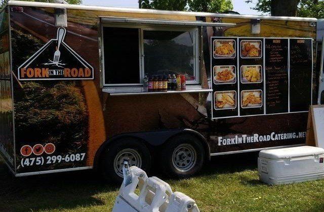 A fork and road food truck is parked in the grass