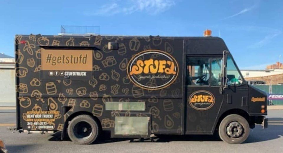 A black and gold food truck is parked on the side of the road.