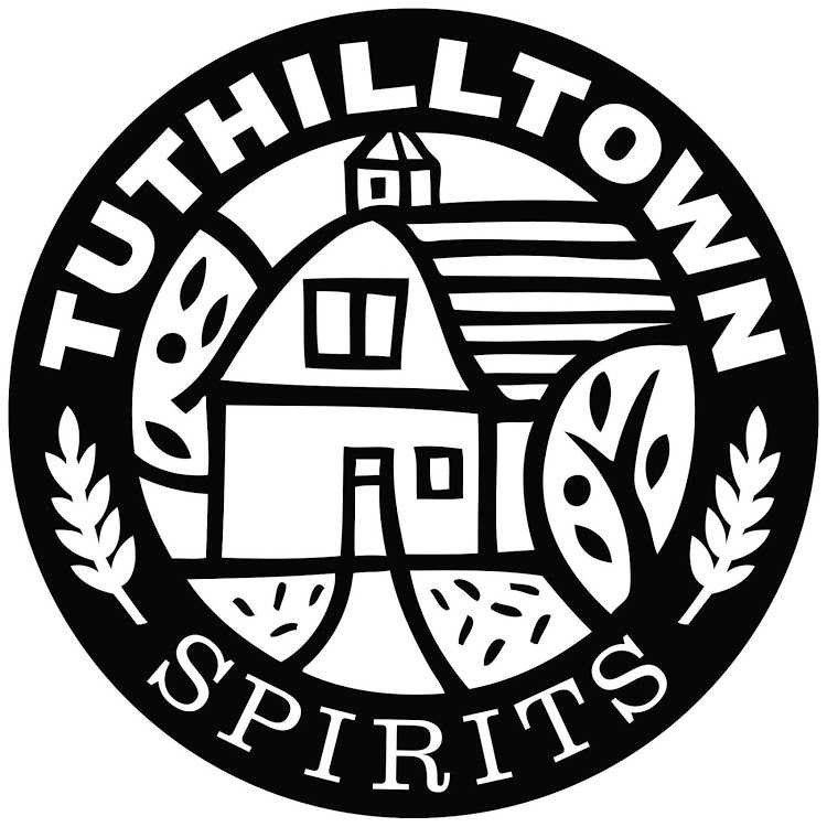 A black and white logo for tuttletown spirits with a barn and leaves in a circle.