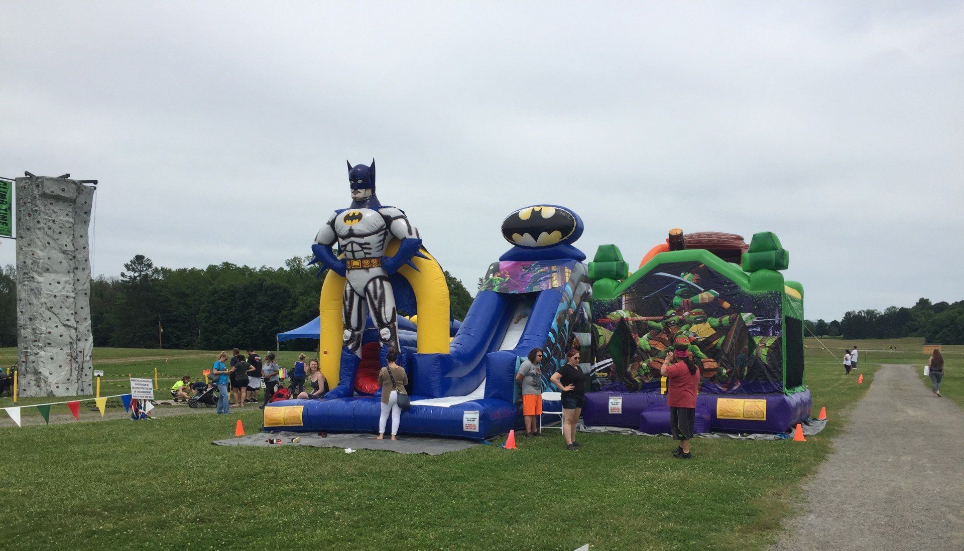 A group of people are playing on a bouncy house in a park.