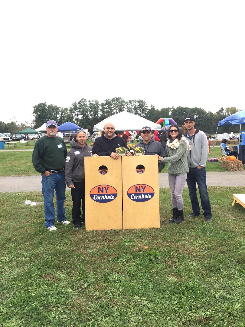 A group of people are standing in a field holding cornhole bags.