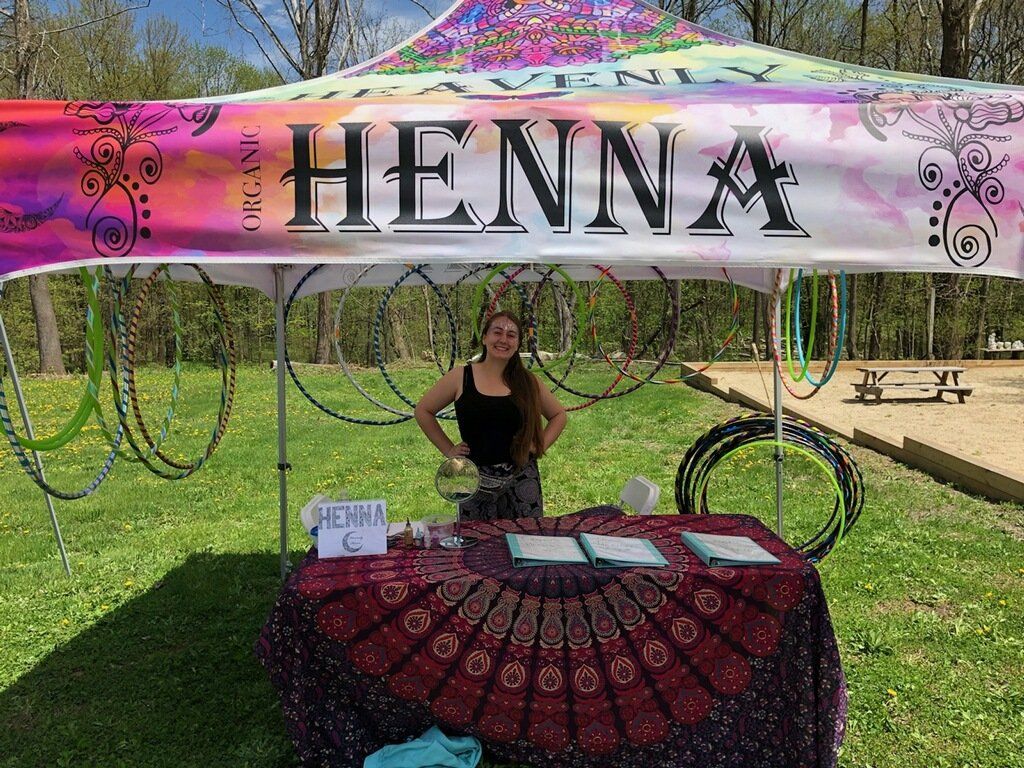 A woman is standing in front of a table under a tent.