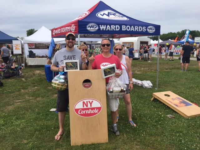 A group of people standing in front of a ny cornhole board