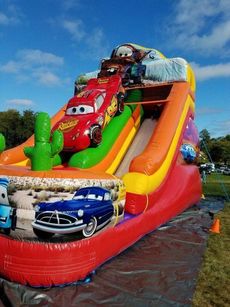 A large inflatable slide with cars on it in a park.