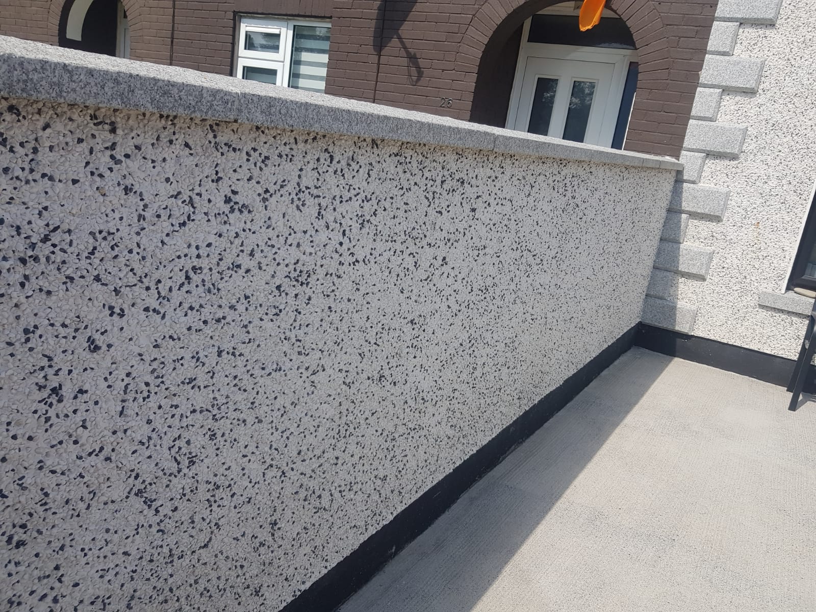 A wall with a brick building in the background