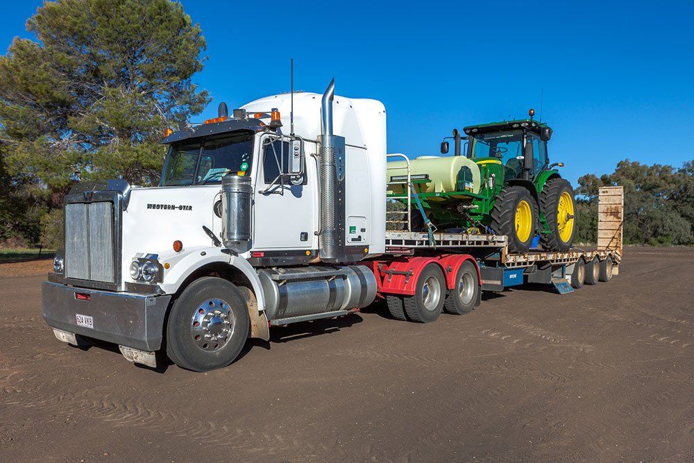 Flatbed truck carrying farm tractor