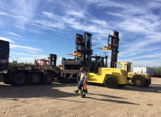 Two cranes placing oversize material onto a flatbed truck