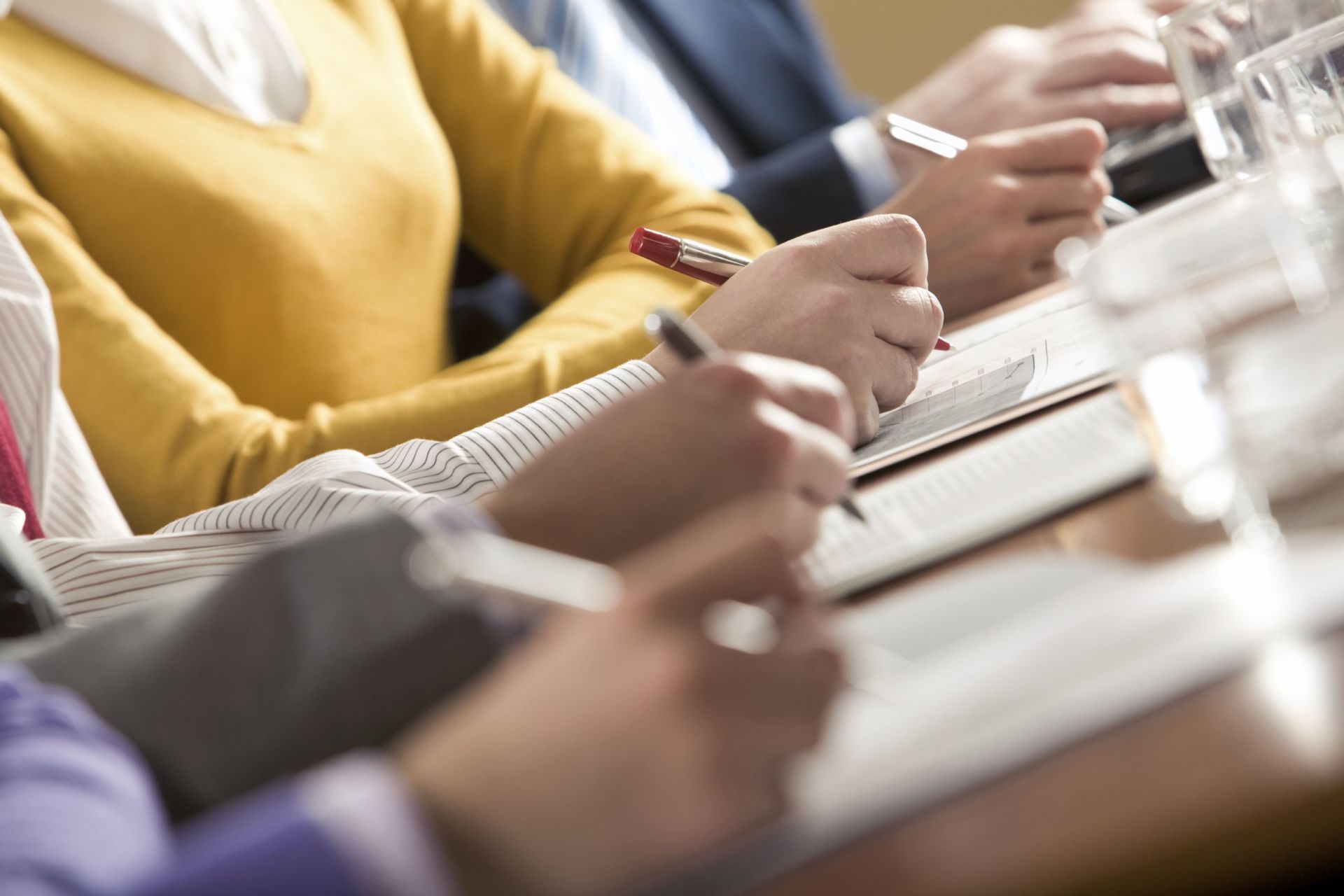 A group of people are sitting at a table writing in notebooks.