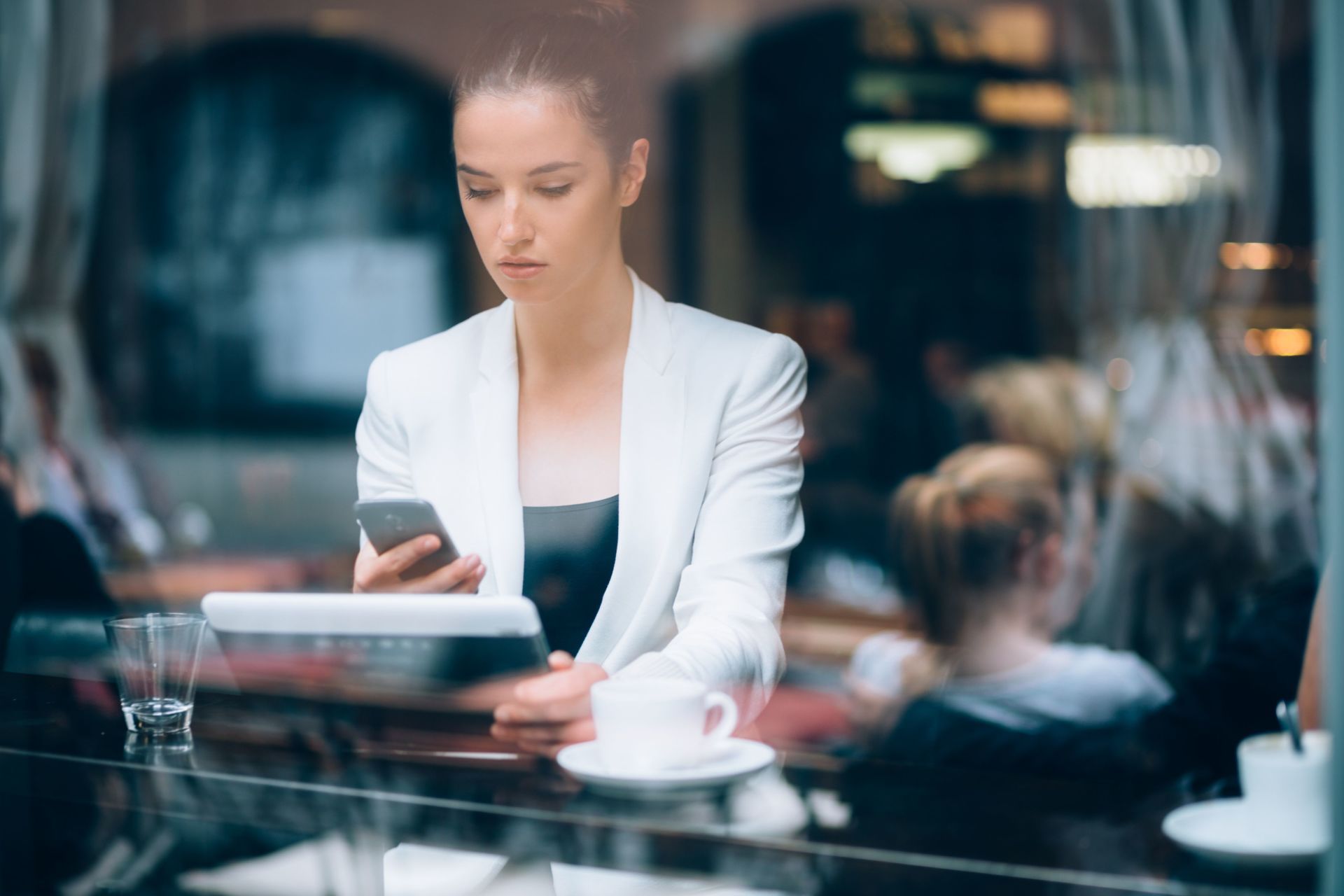 A woman is sitting at a table in a restaurant looking at her phone.