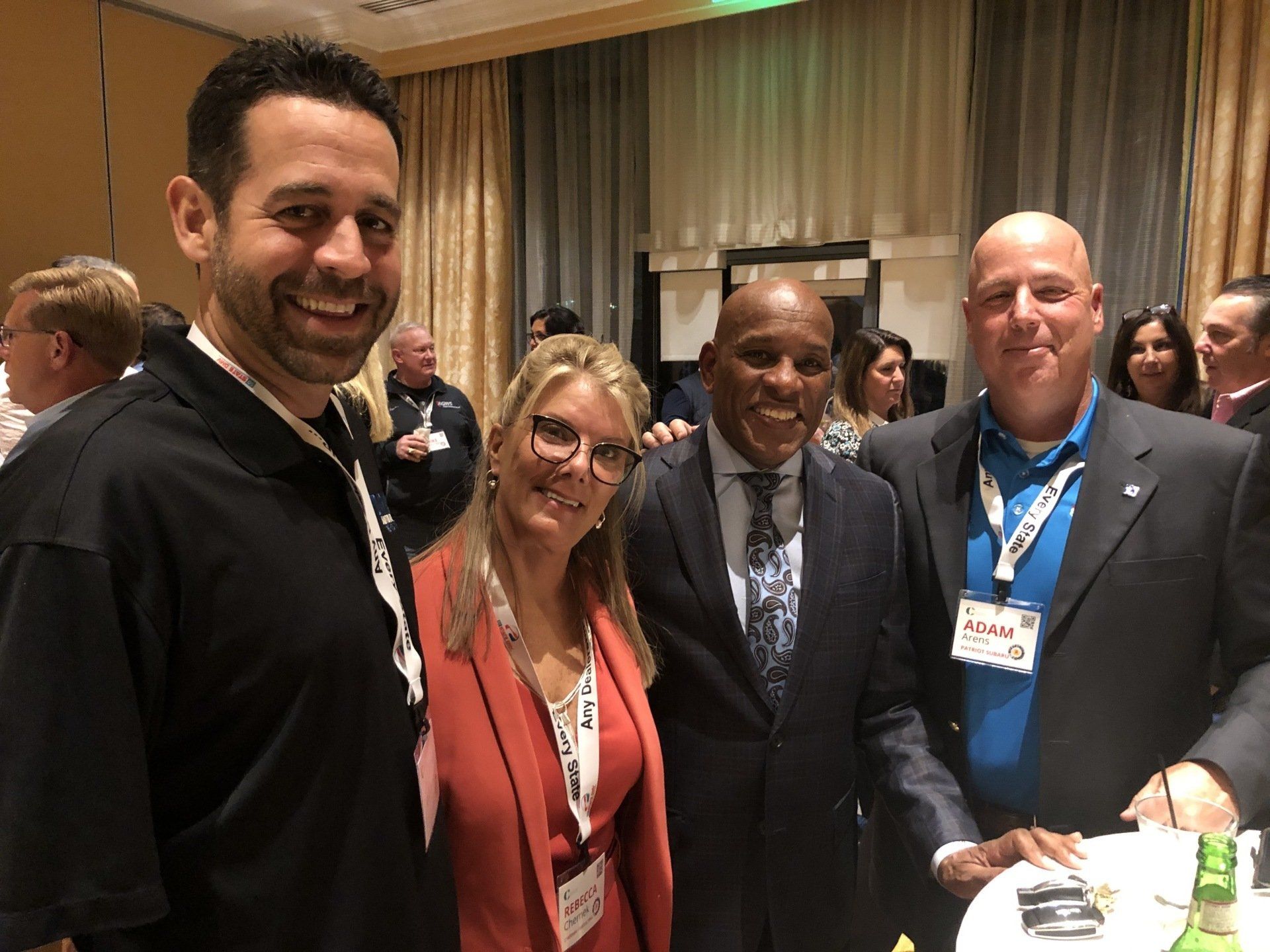 Four people smiling, posing together indoors at an event.