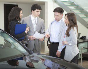 A group of people are looking at a car in a showroom.