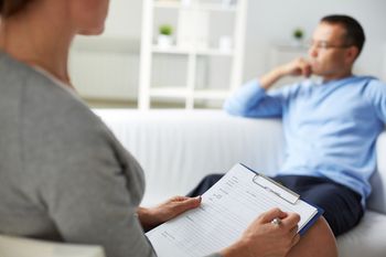 Psychologist treating man who is sitting on a couch thinking