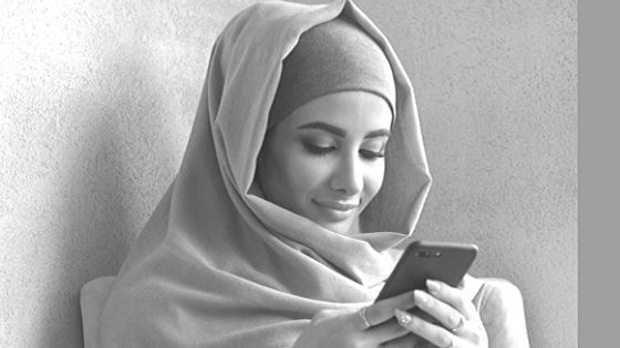 A woman in a hijab is looking at her cell phone.